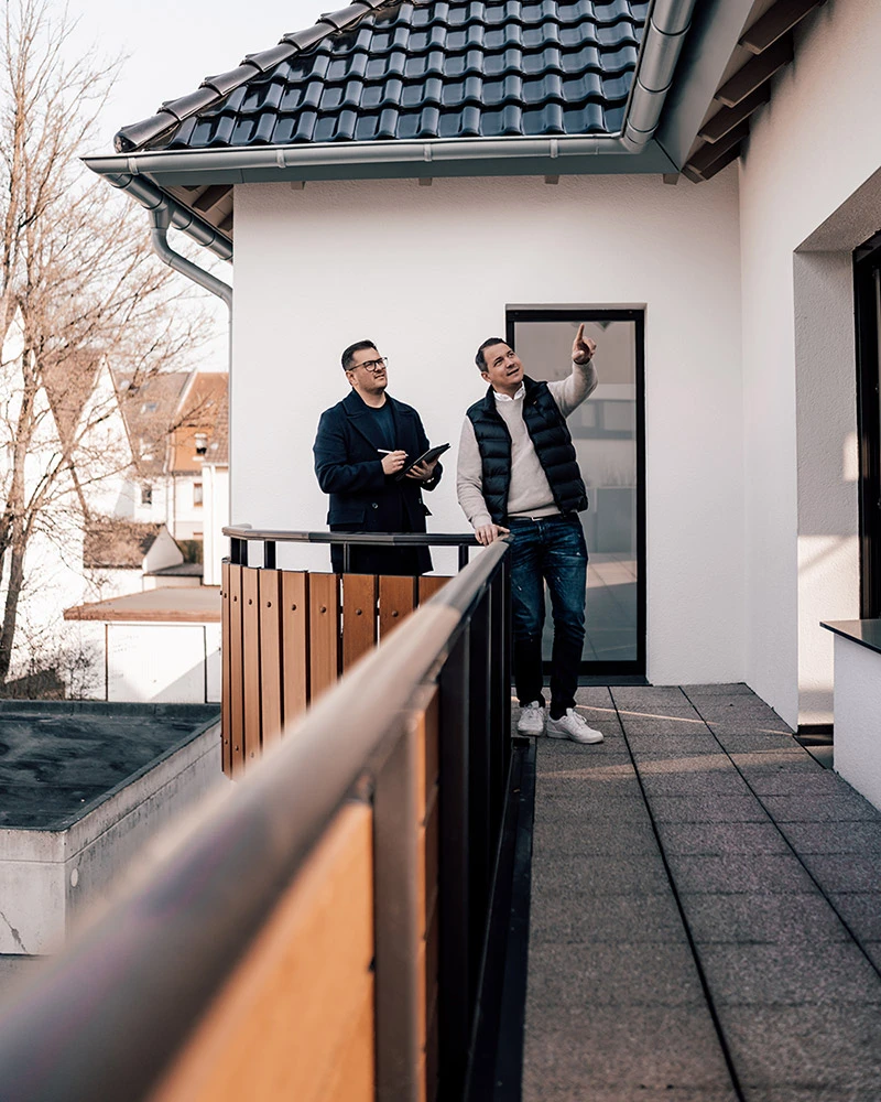 Zwei Makler von Engelsburg Immobilien im Gespräch auf der Terrasse eines Hauses